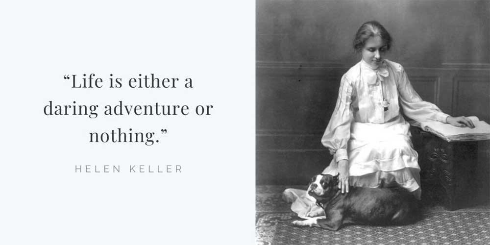 Helen Keller sitting on the floor, petting her dog and reading a braille book.