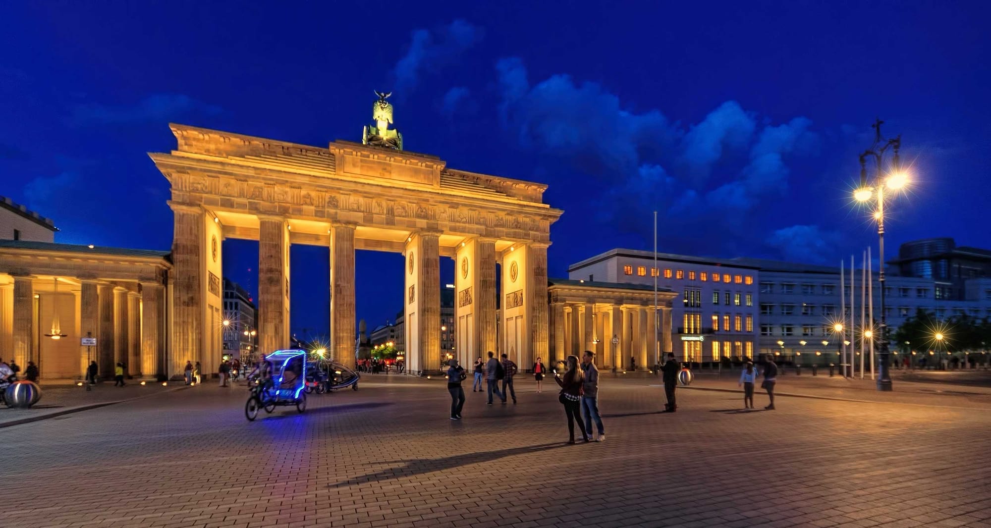 Brandenburg Gate against a dark blue sky at night.