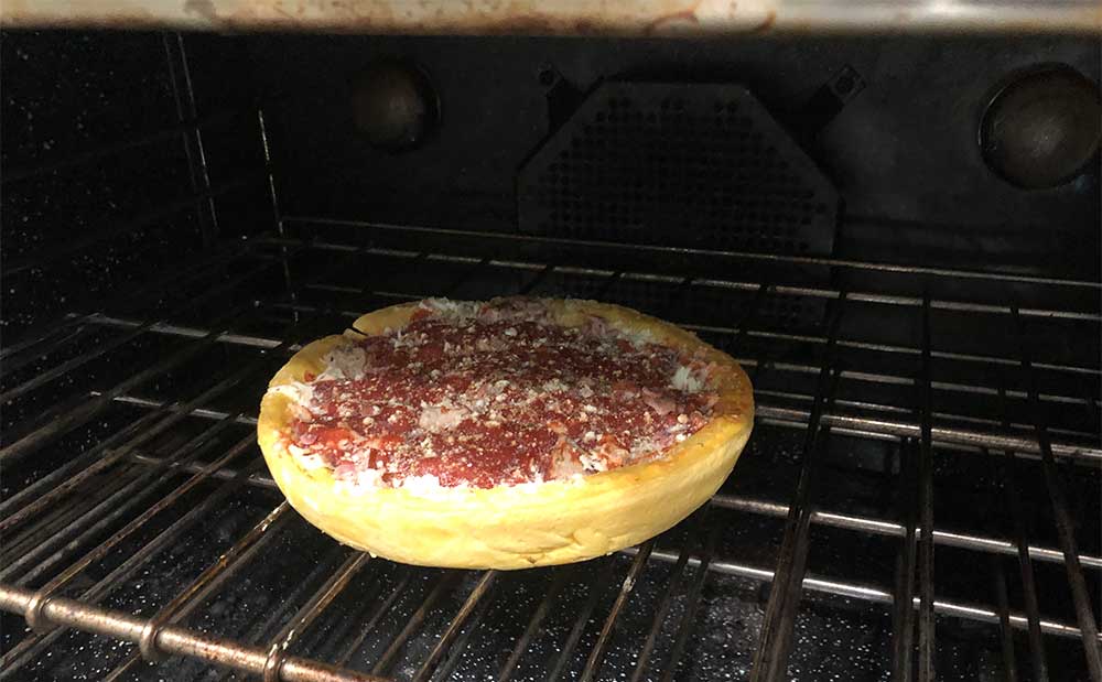 Frozen pizza on oven rack.