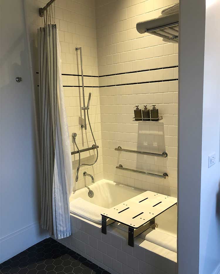 Bathtub with grabs bars, shower chair and handheld shower head.