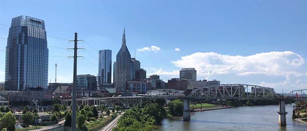 John Seigenthaler Pedestrian Bridge crossing the river in front of the Nashville skyline.