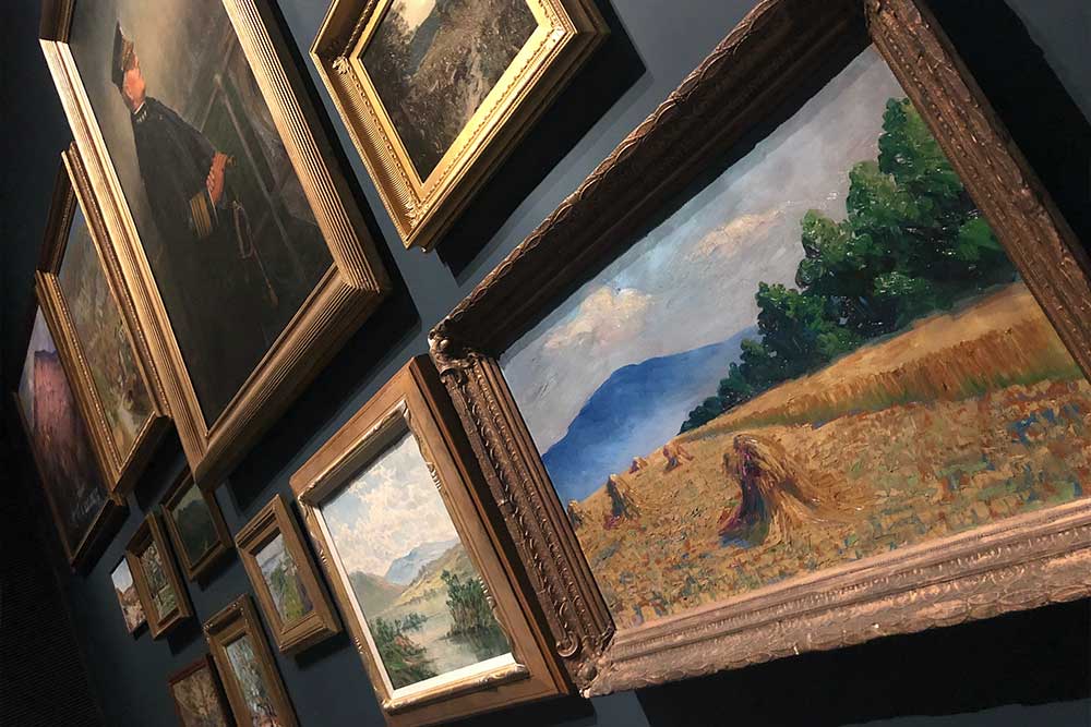 Group of paintings hanging on the wall at a museum.