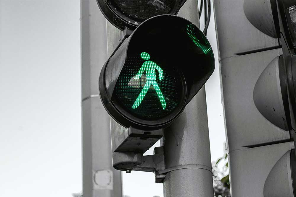 Close-up of crosswalk pedestrian signal with green icon of man walking illuminated.