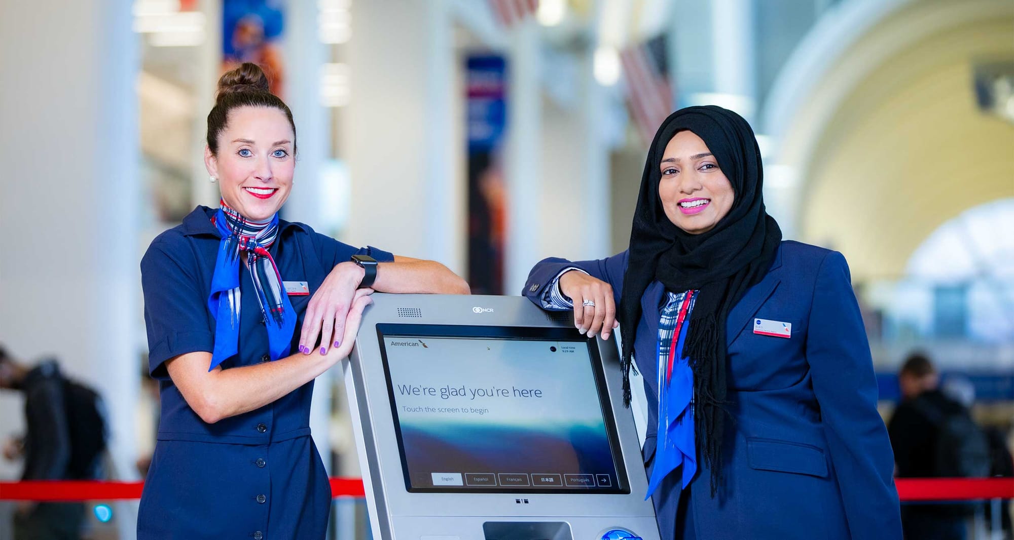 Two American Airlines team members standing at an airport kiosk.