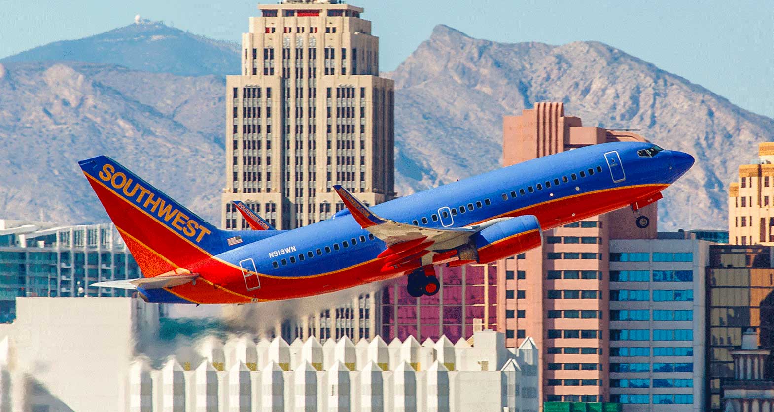 Southwest Airlines Boeing 737 inn takeoff climb; tall buildings in background.