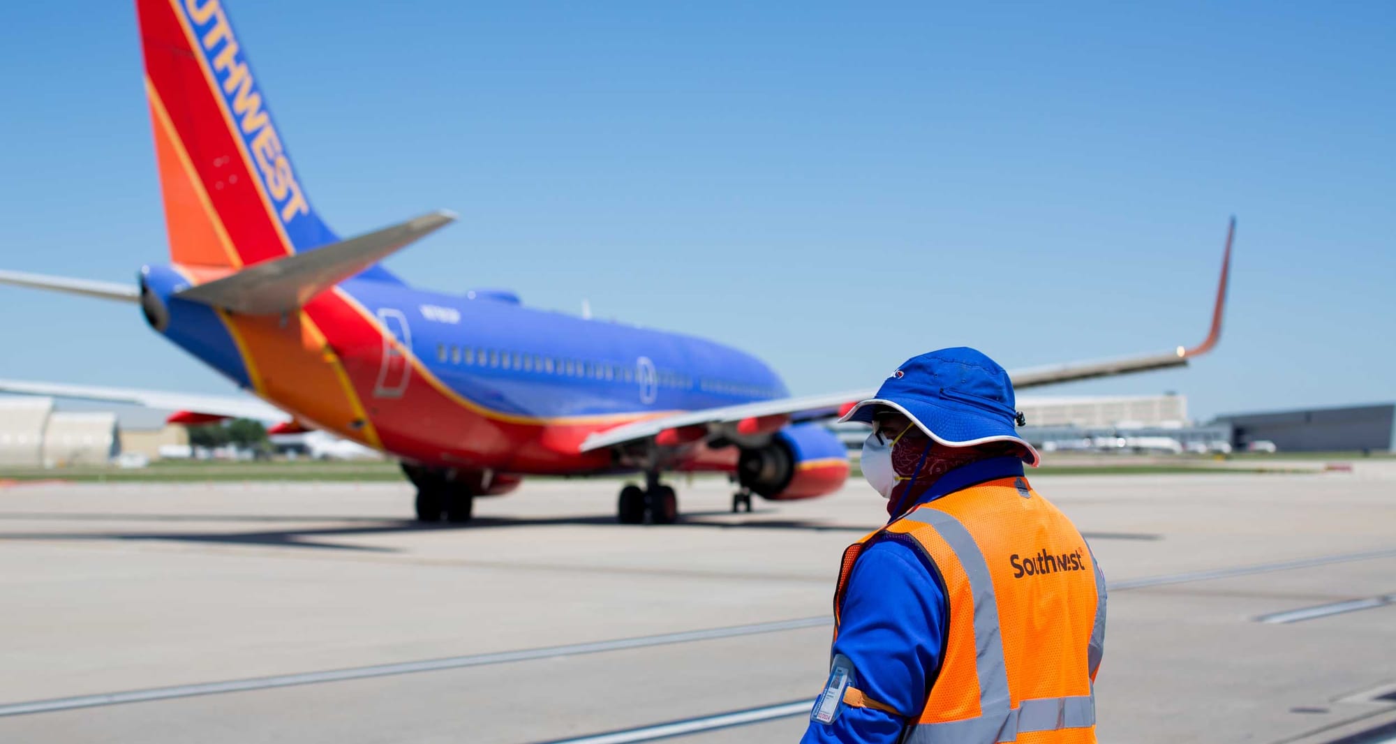 Airline employee watches from tarmac as Southwest Airlines jet taxis away.