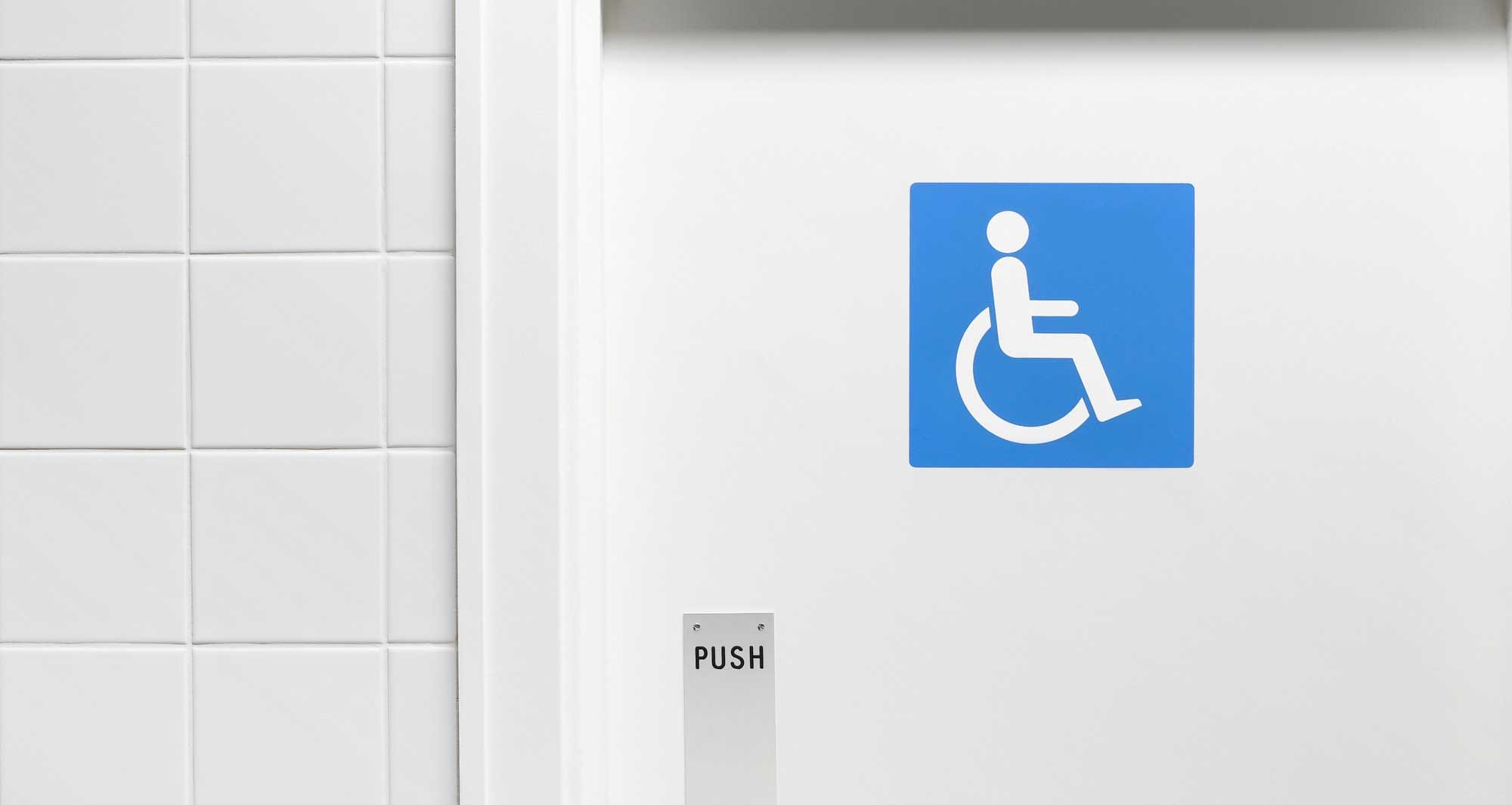 Blue wheelchair icon on white door to bathroom.