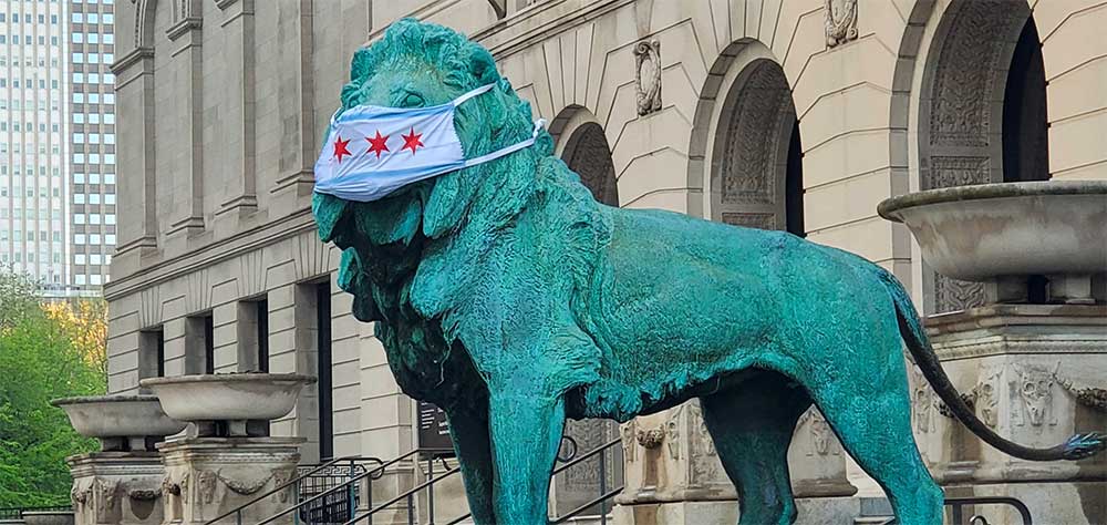 Lion sculpture outside of the Arts Institute of Chicago with a mask covering its face.