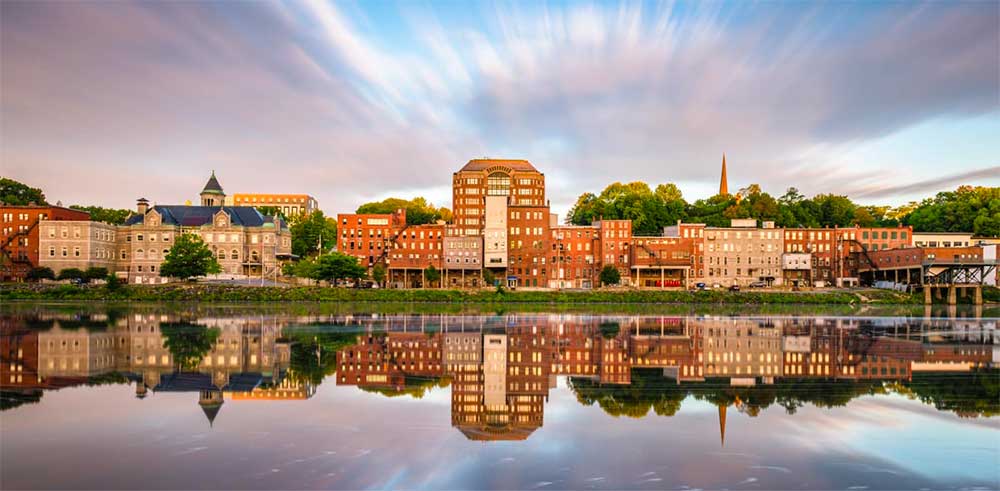 Augusta, Maine skyline reflecting onto a body of water.