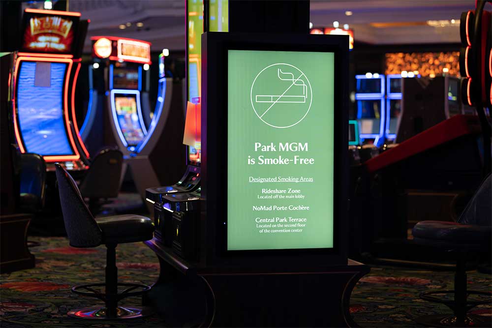 Green sign on casino floor that says Park MGM is smoke-free.