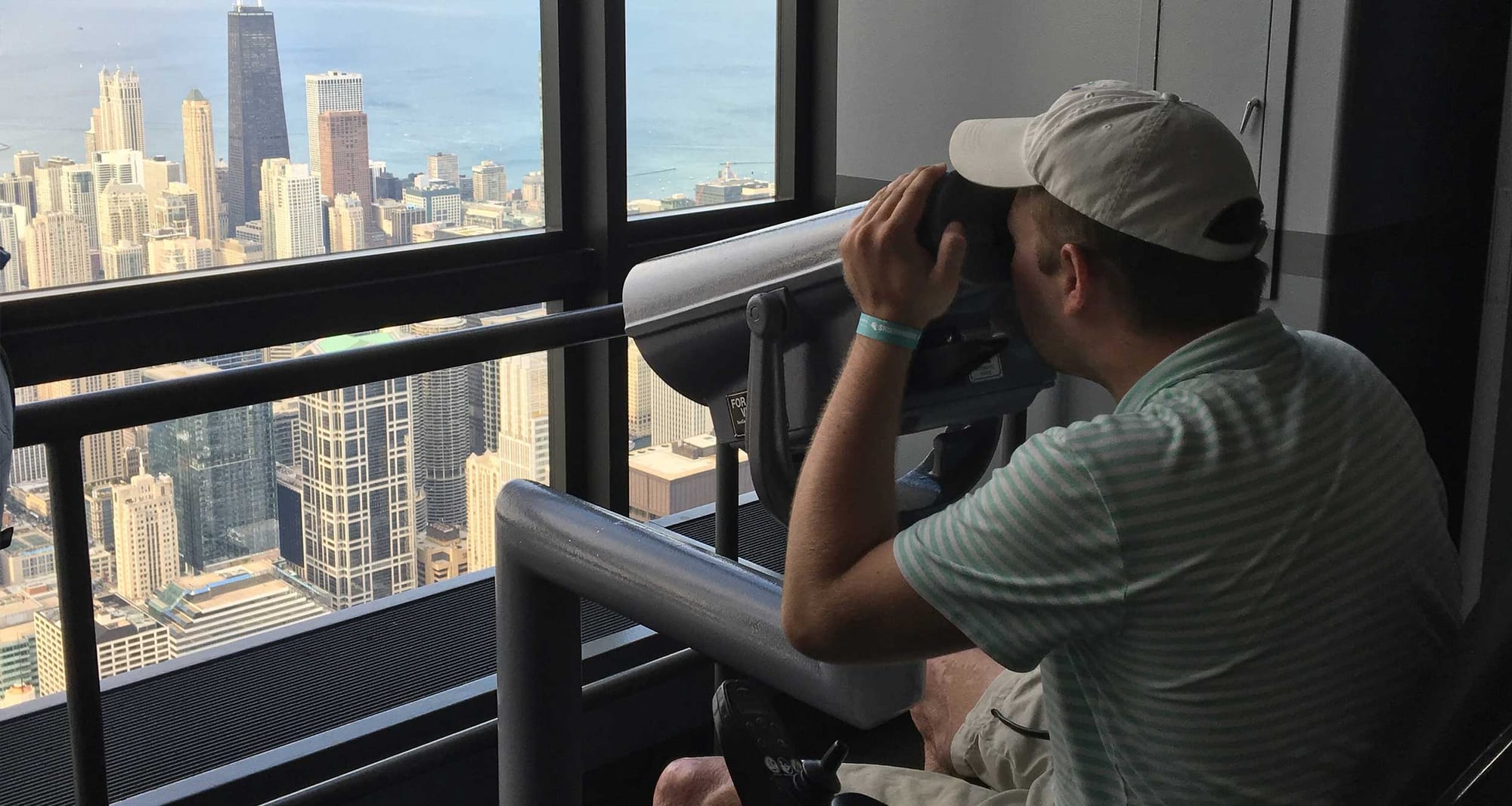 Wheelchair user looking at city skyline through accessible viewfinder.