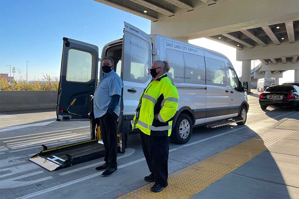 Hotel shuttle with wheelchair lift deployed from back of van.