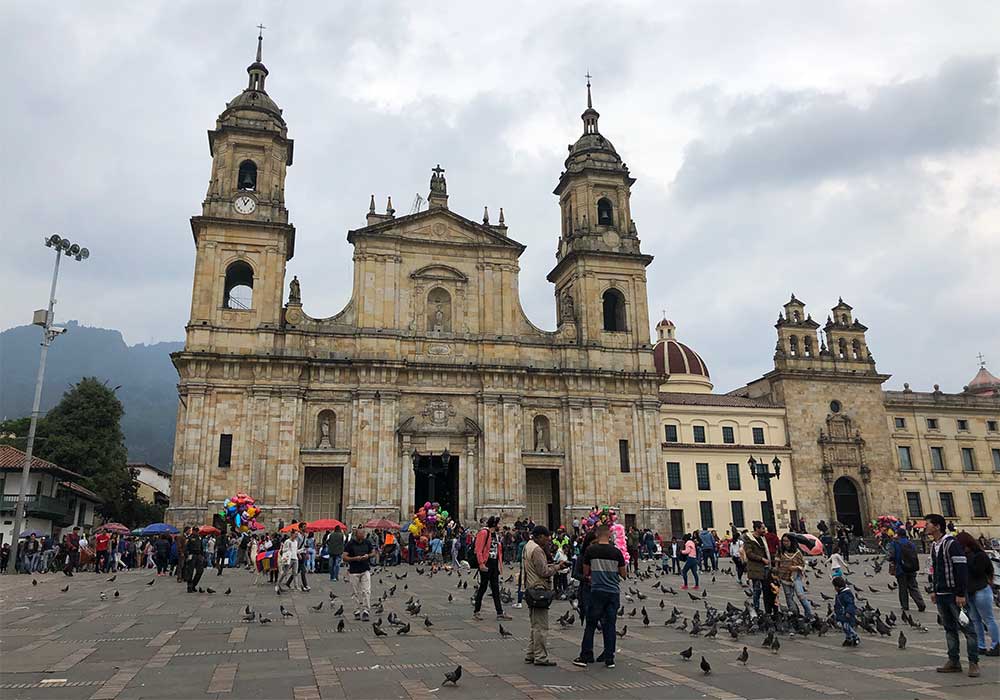 Catholic cathedral on Bolivar square, filled with people and pigeons.