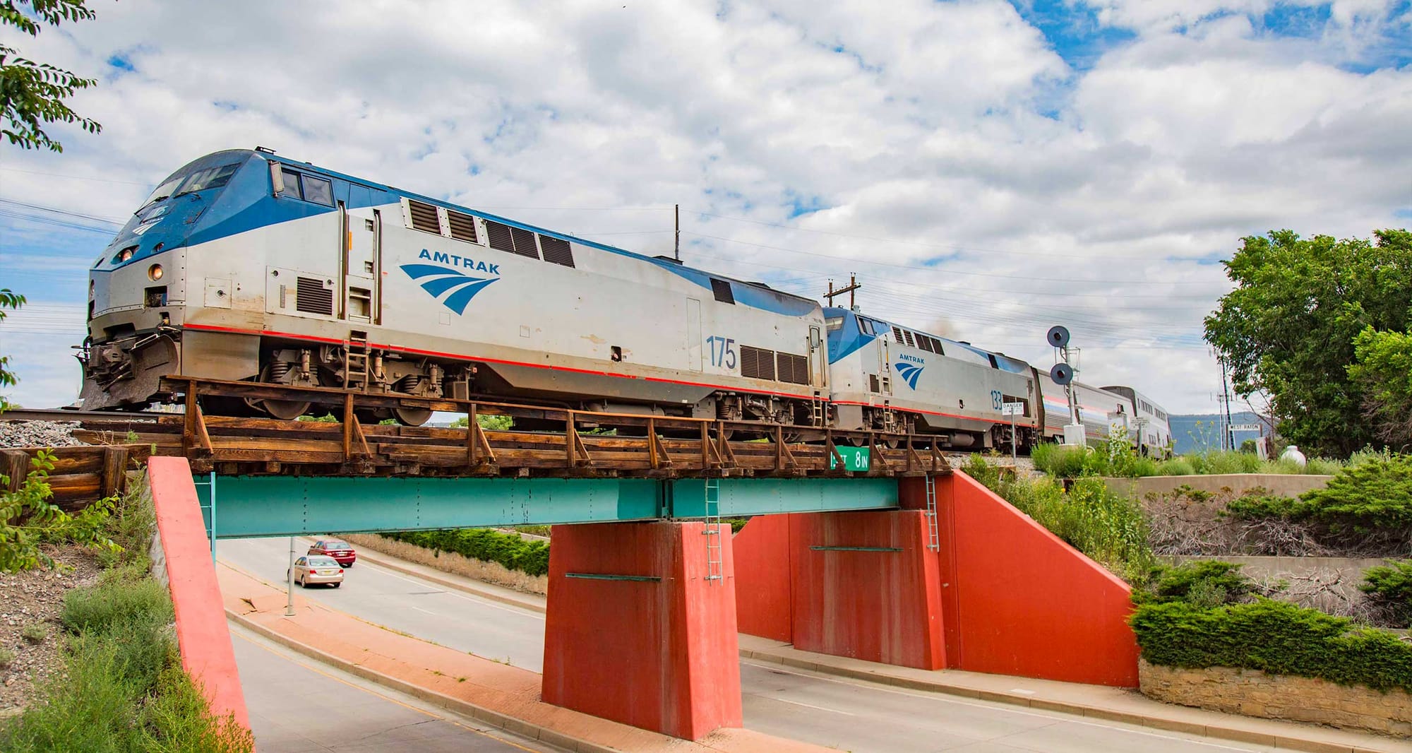 Amtrak train crossing bridge over roadway.