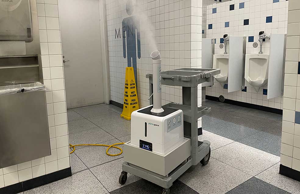 Device spraying disinfectant into airport bathroom.