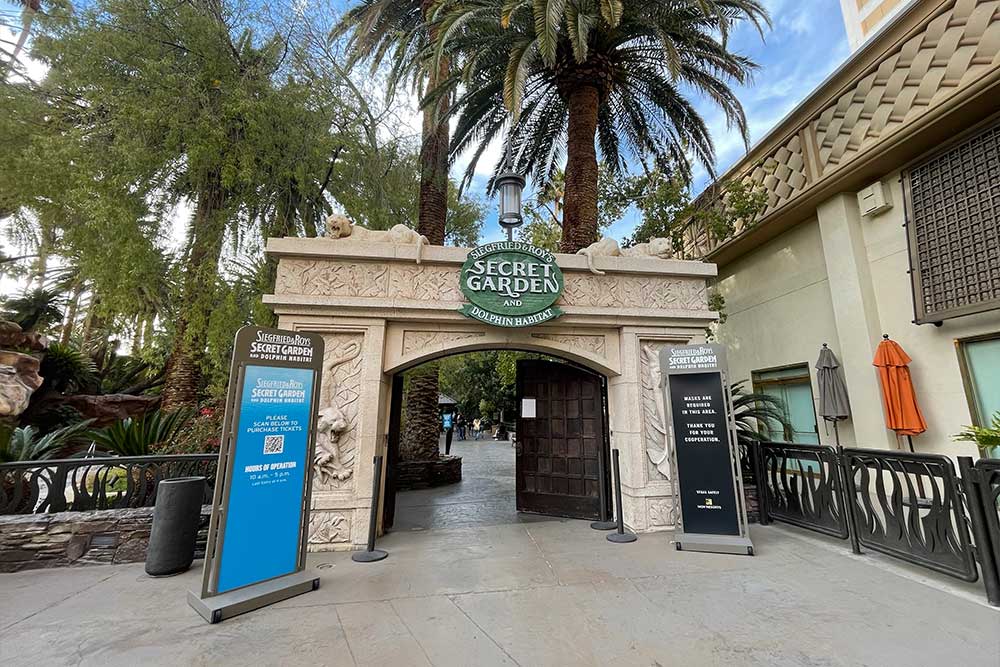 Entrance gate to Secret Garden with sign and two large wooden doors opened.