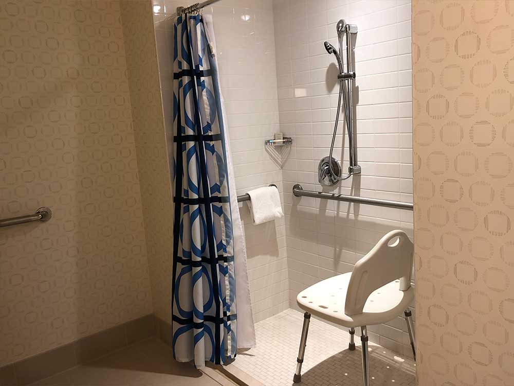 Roll-in shower with plastic chair.