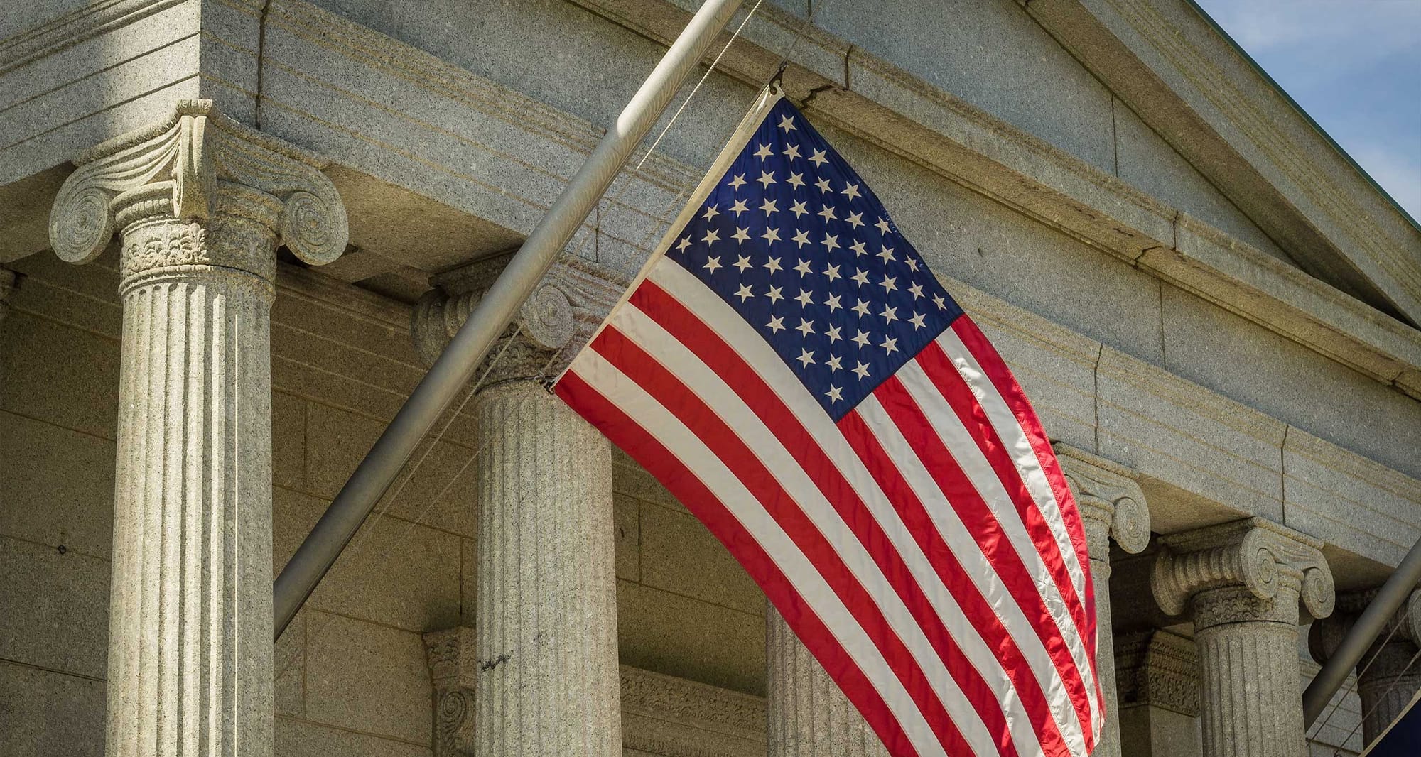 United States flag hanging from the side of a building with columns.