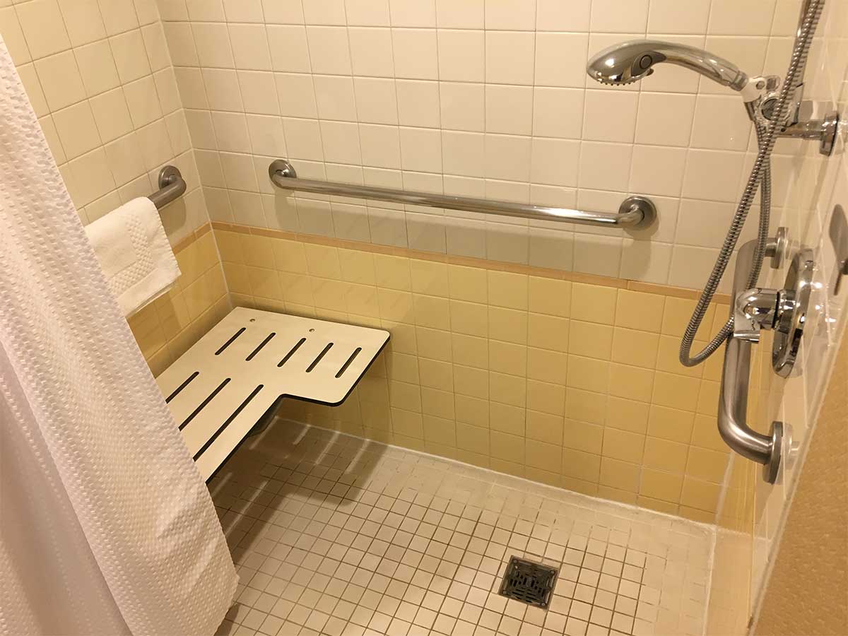 Roll-in shower with built-in seat on wall opposite the controls.