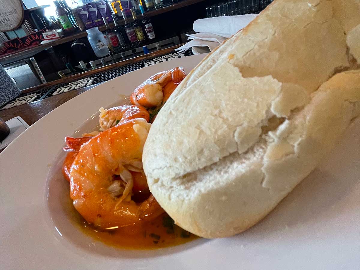 Large shrimp in a bowl with a piece of French bread.