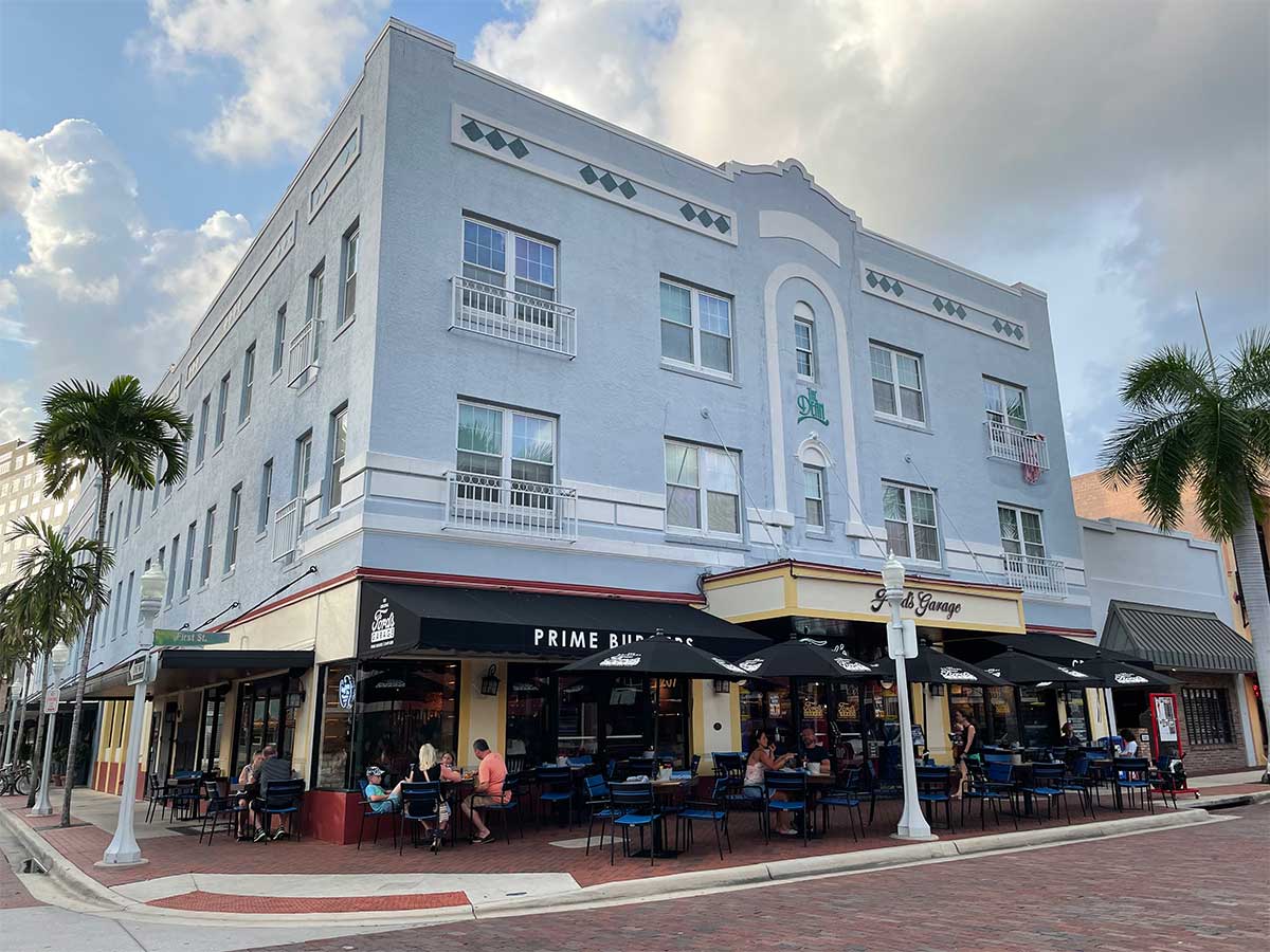 Three story historic building on street corner, restaurant on ground floor with outdoor seating on sidewalk.