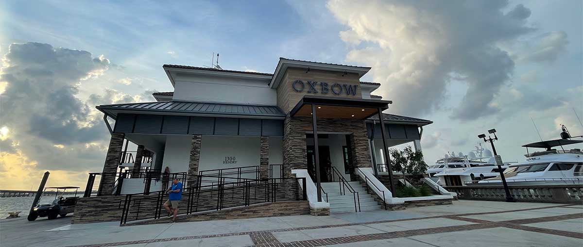 Exterior of Oxbow restaurant building on the waterfront with a wheelchair ramp into the building.