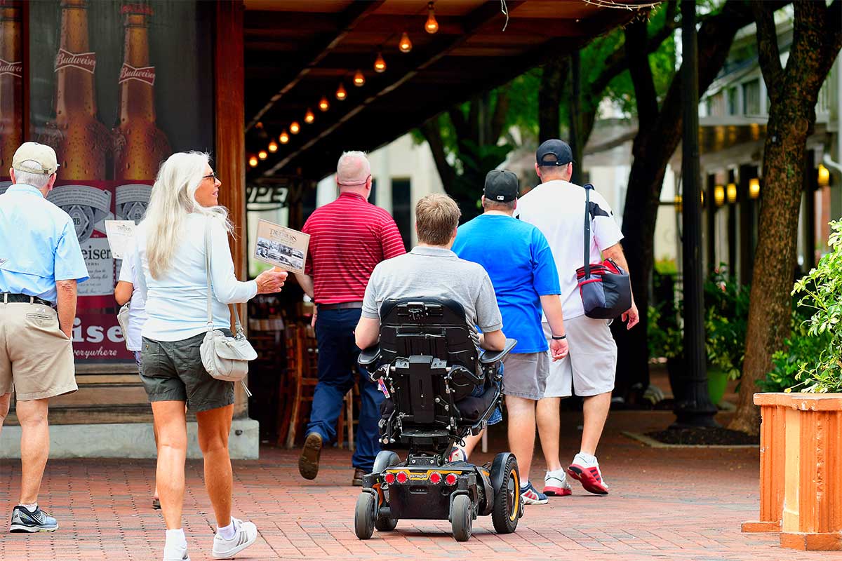 John following the walking tour group in his wheelchair.