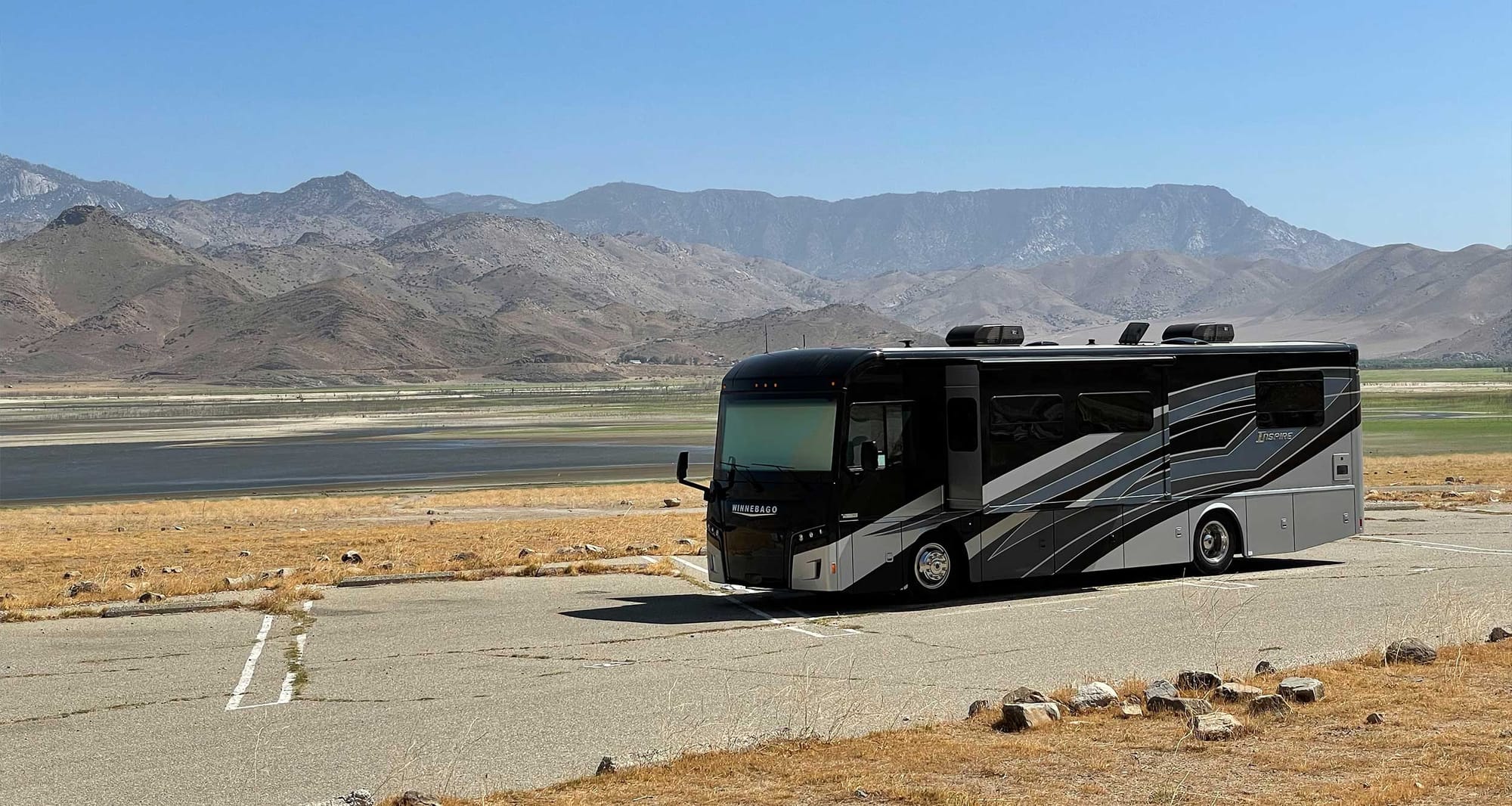 Winnebago Inspire parked in front of lake and mountains.