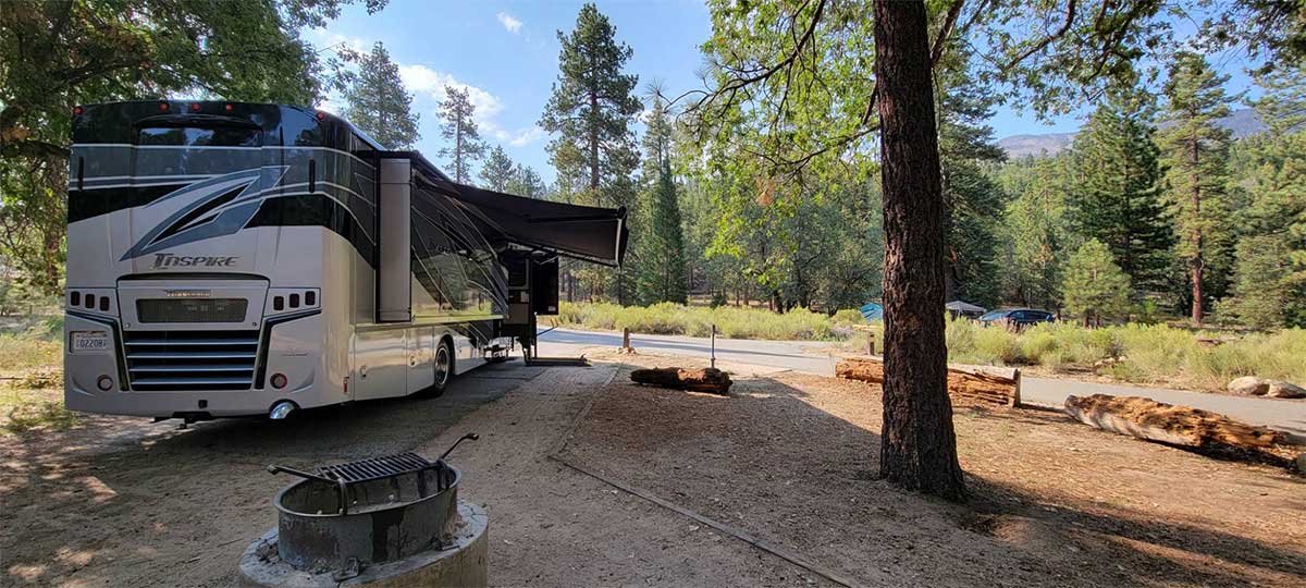 Winnebago Inspire parked at campsite with shade awnings deployed.