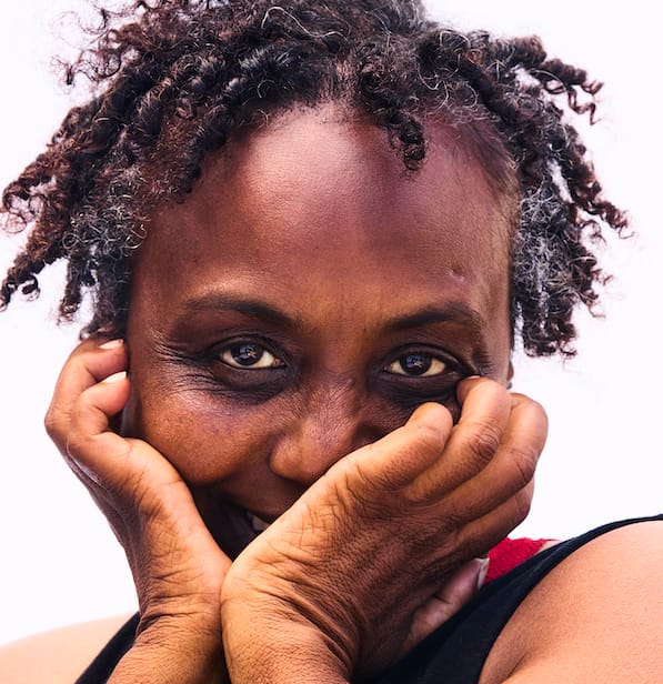 Close-up image of black woman with hands clutching face.