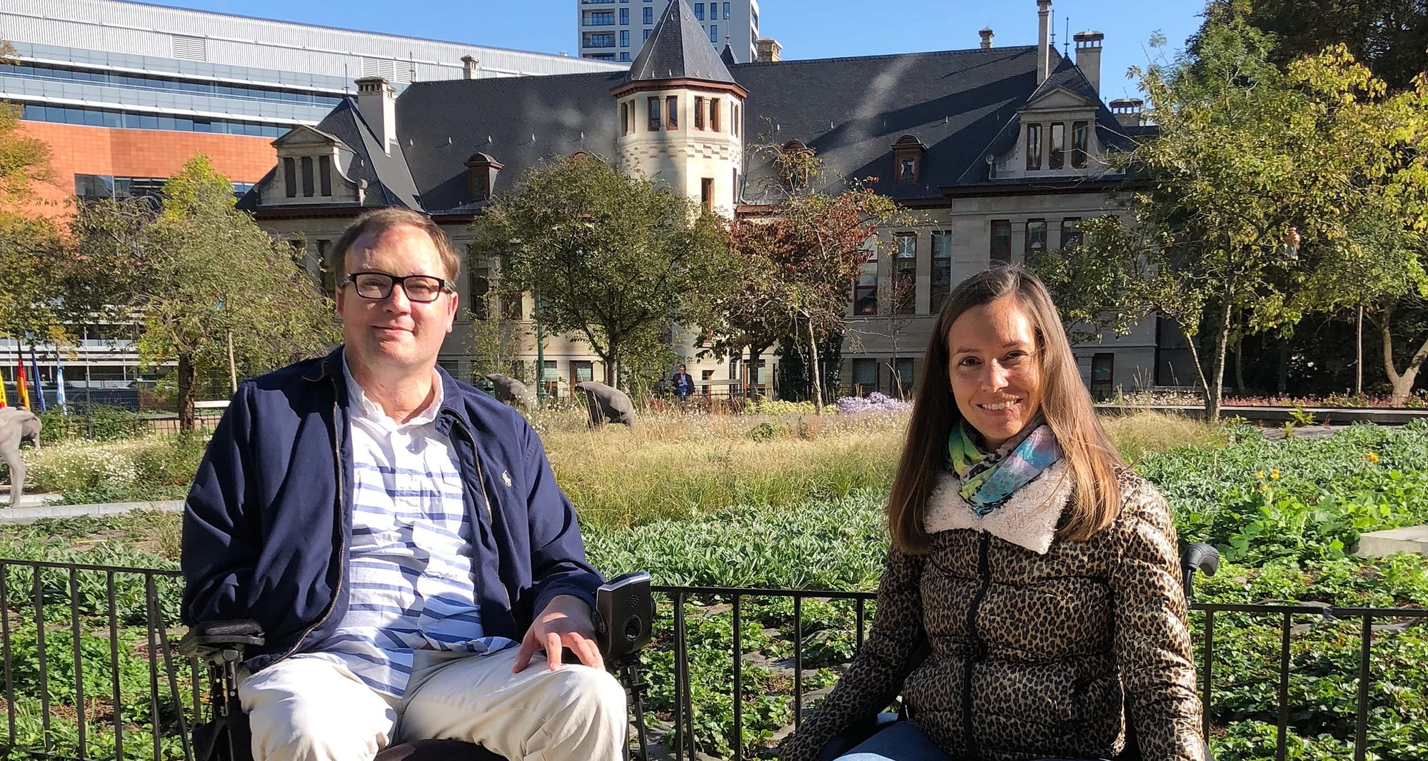 Two wheelchair users sitting in front of a garden.