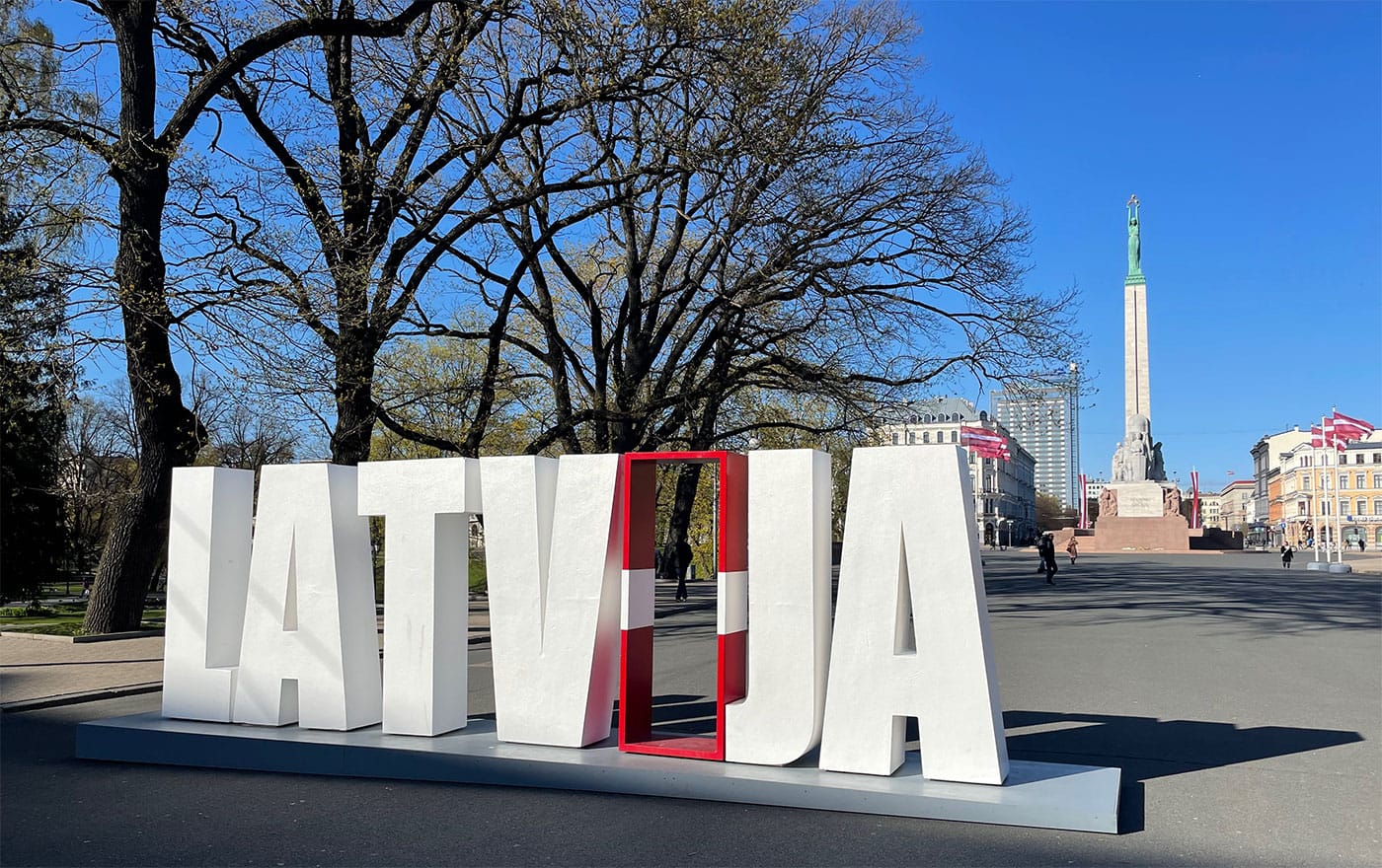 Latvia letters sign in front of towering Freedom Monument.