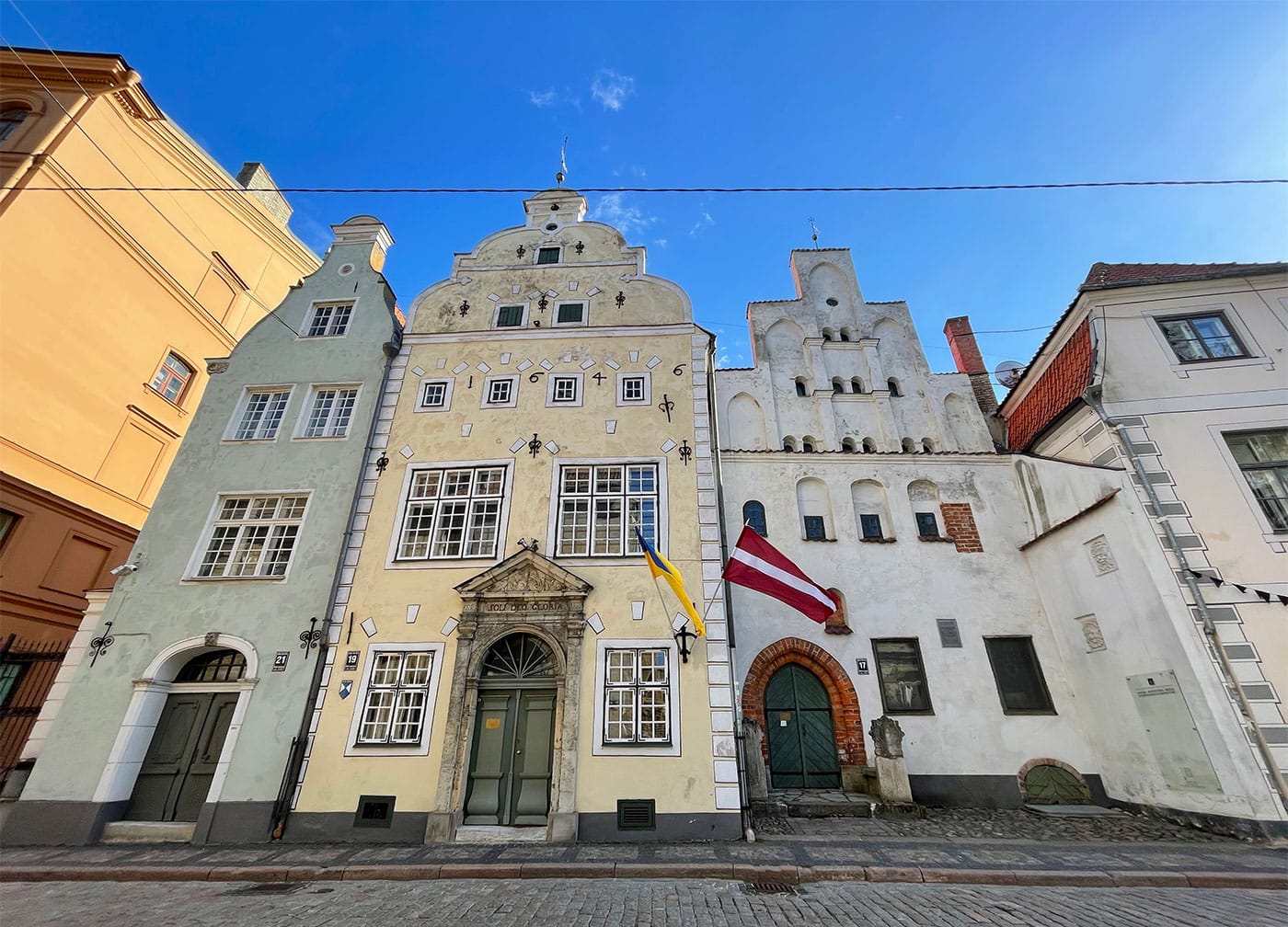 Three historic buildings in a row, painted in pastel colors.