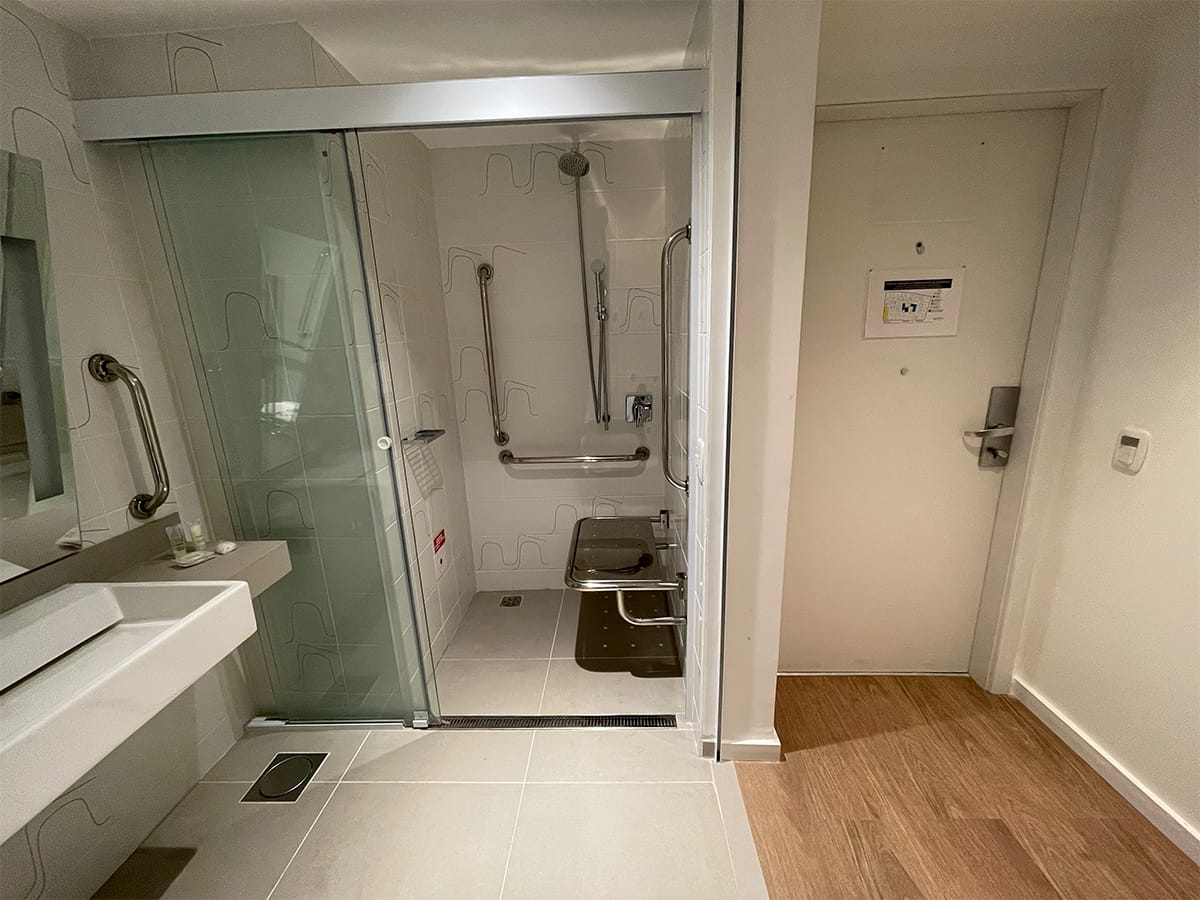 Square roll-in shower with a sliding glass door.