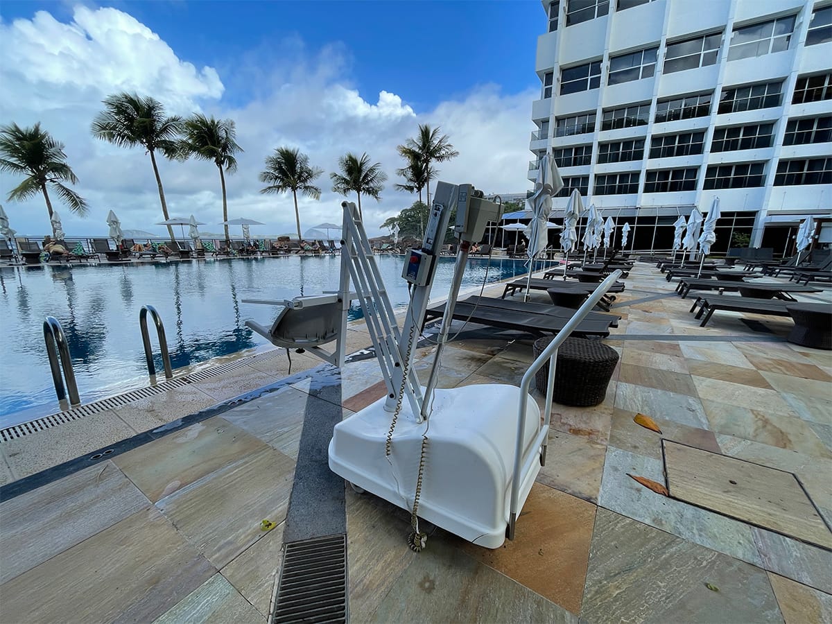 Portable swimming pool lift for wheelchair users next to the pool.