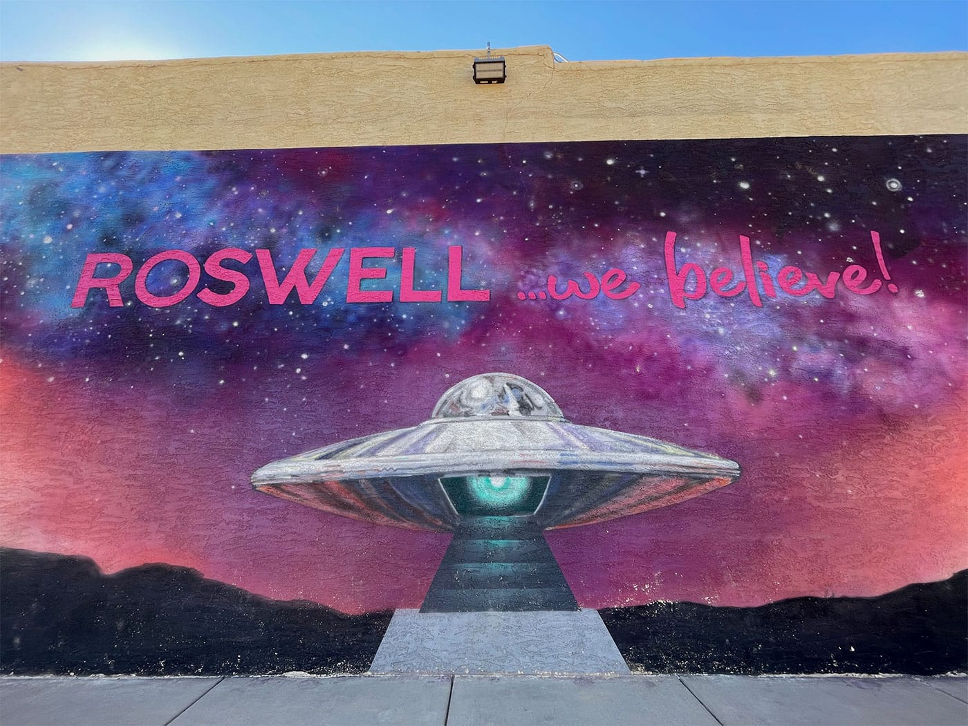 Mural on exterior of UFO museum with a spaceship and the words Roswell, we believe.