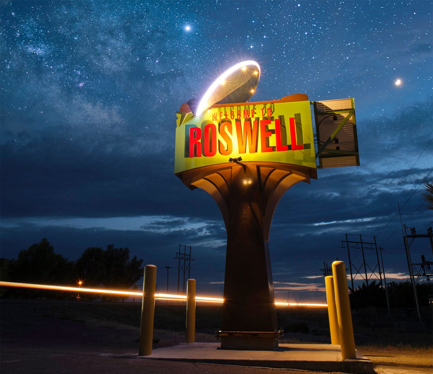 Welcome to Roswell sign featuring a UFO saucer against a blue starry sky.