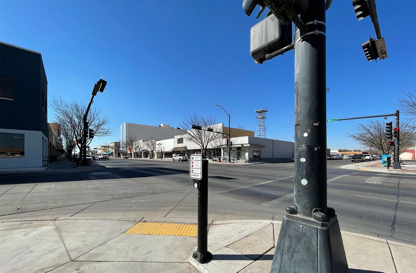 Intersection with accessible crosswalk and curb ramp, crossing signs and an easily accessible crossing button.