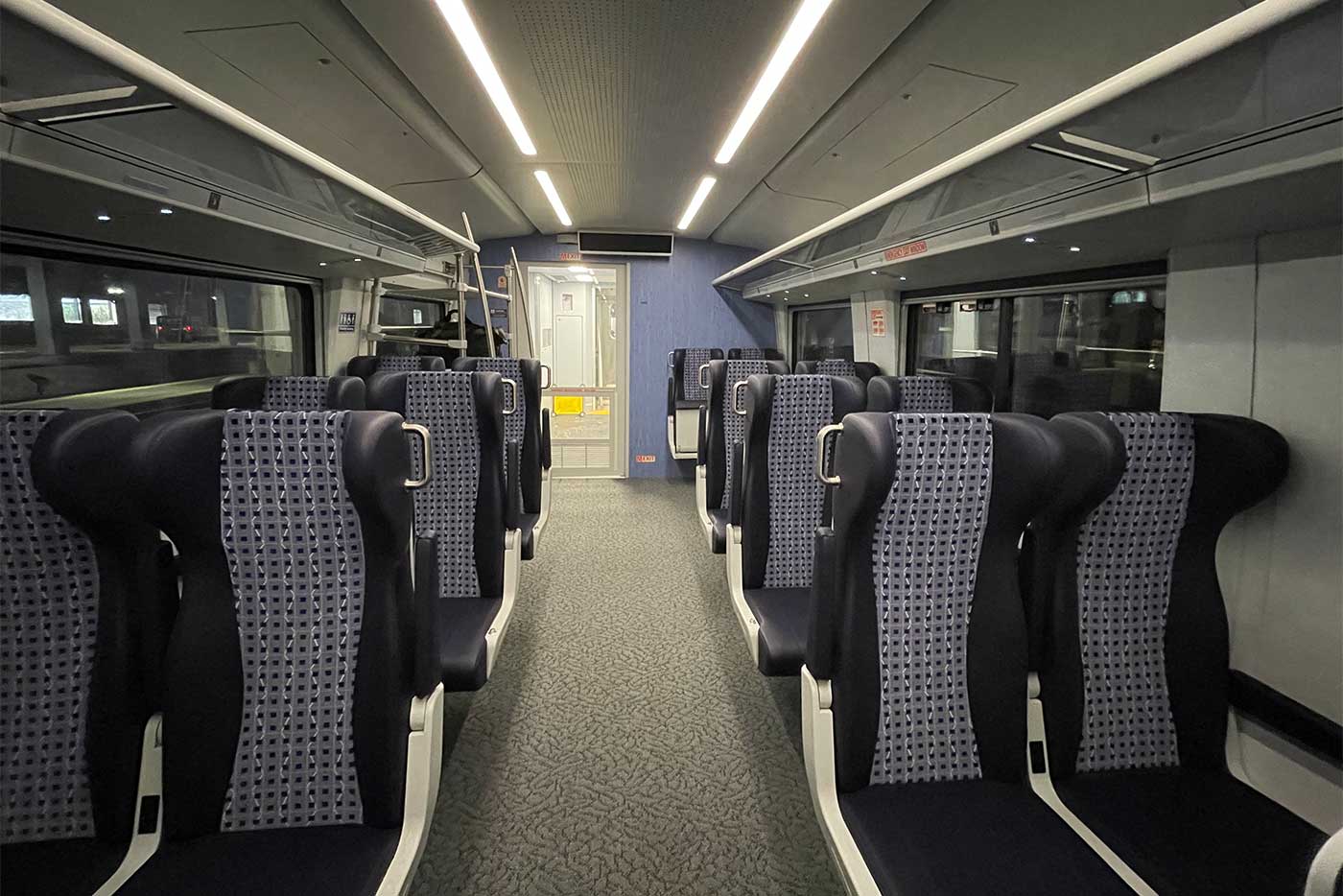 Interior of Amtrak train with seats and wide aisle.