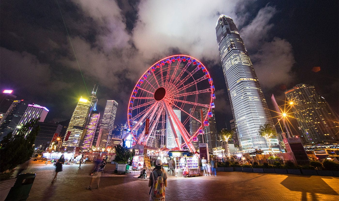 Observation wheel against Hong Kong city skyline at night.