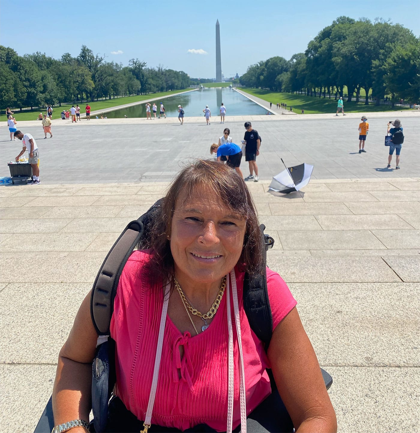 Mary Khan wearing a pink shirt, seated in her wheelchair on the National Mall in Washington DC.