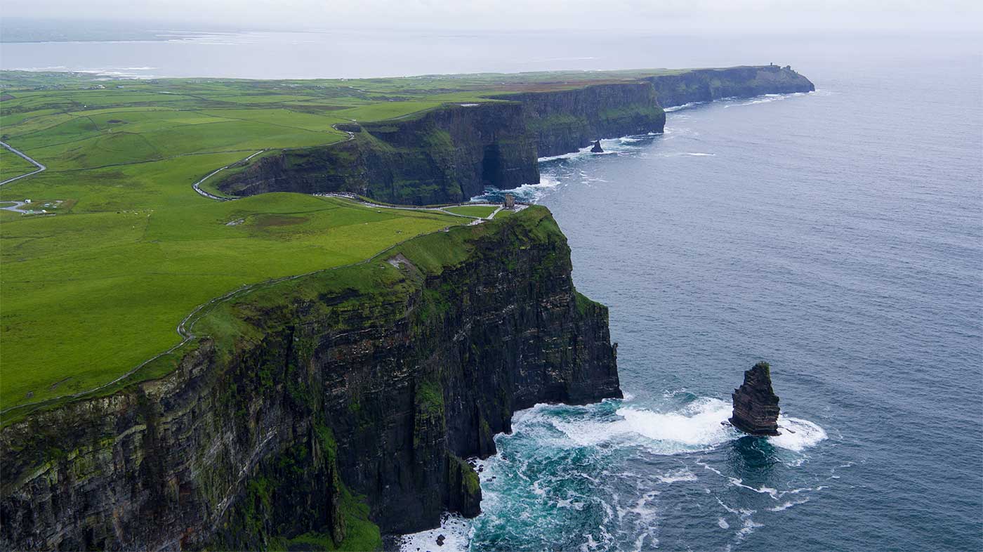 Green grass atop rocky cliffs alongside the water.