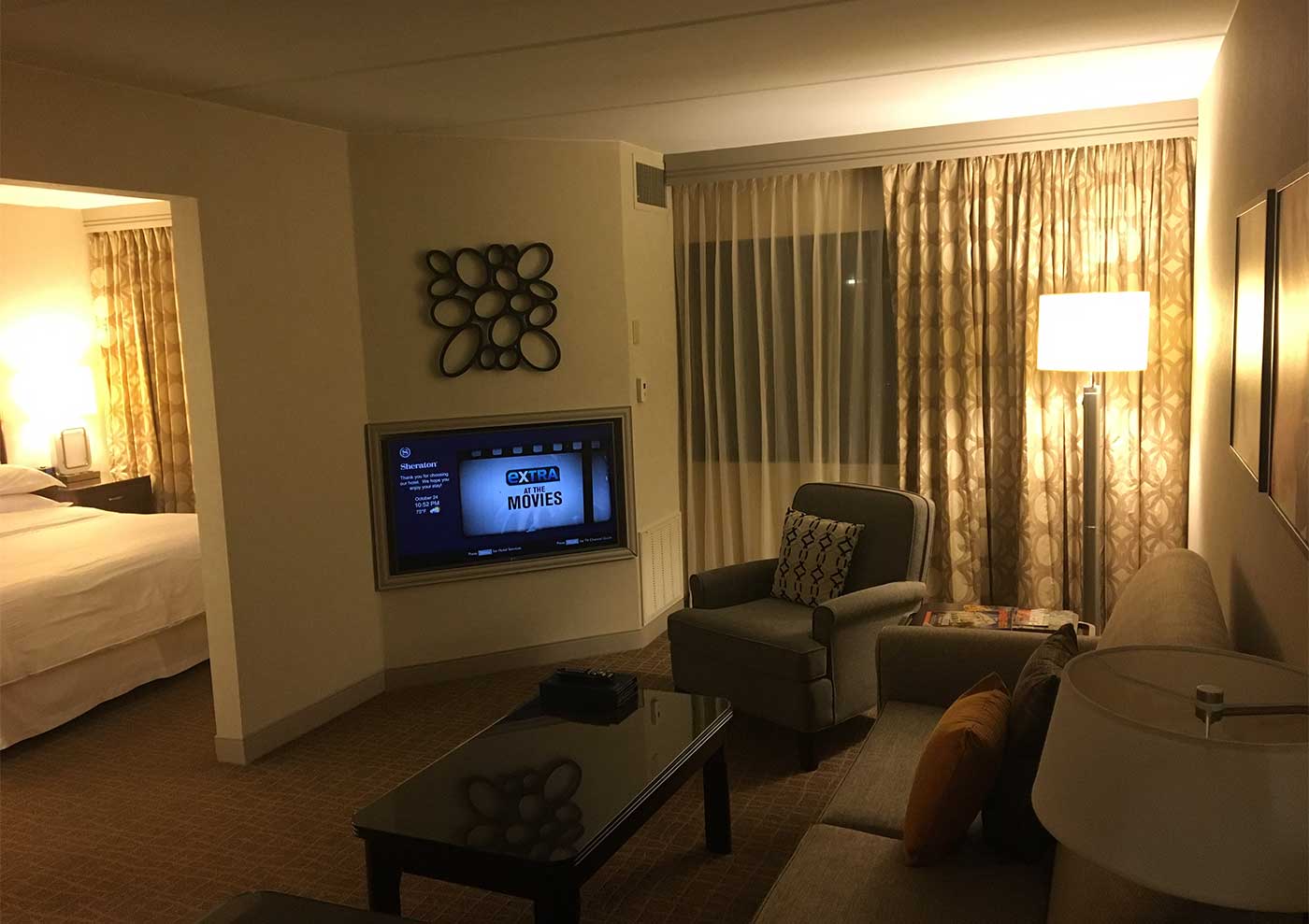 Living room of suite with sofa, chairs, table and TV.