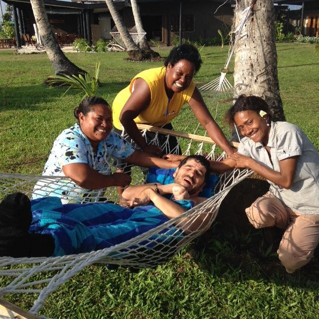 Gordon relaxing in a hammock surrounded by Fijian women.