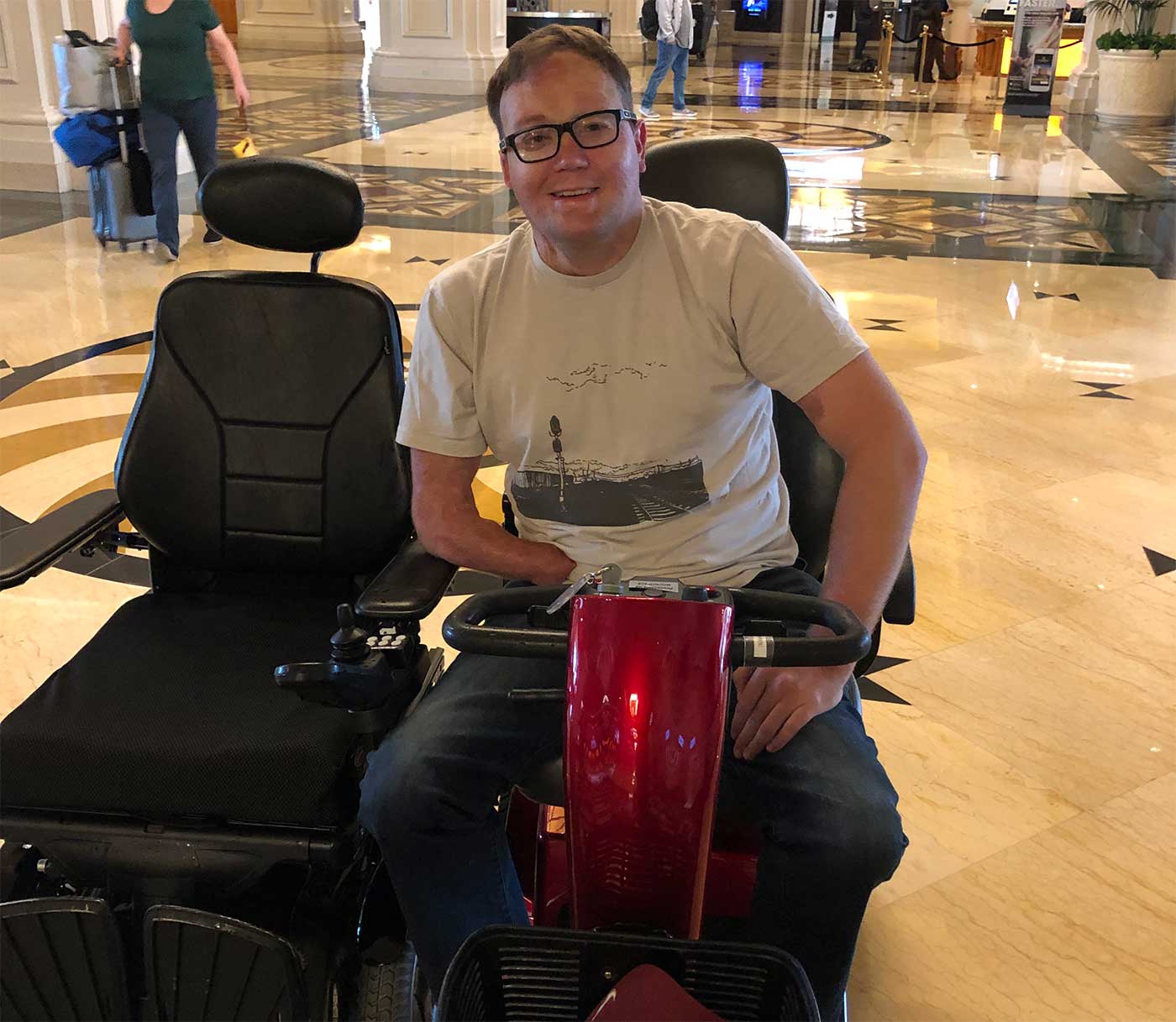 John sitting in a mobility scooter next to a power wheelchair.