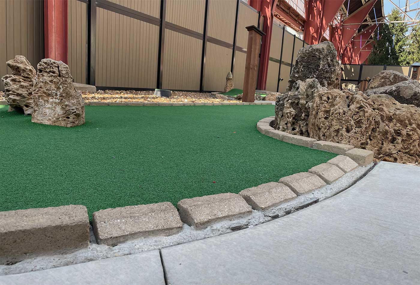 Lowered height curb at the exit to a mini golf hole.