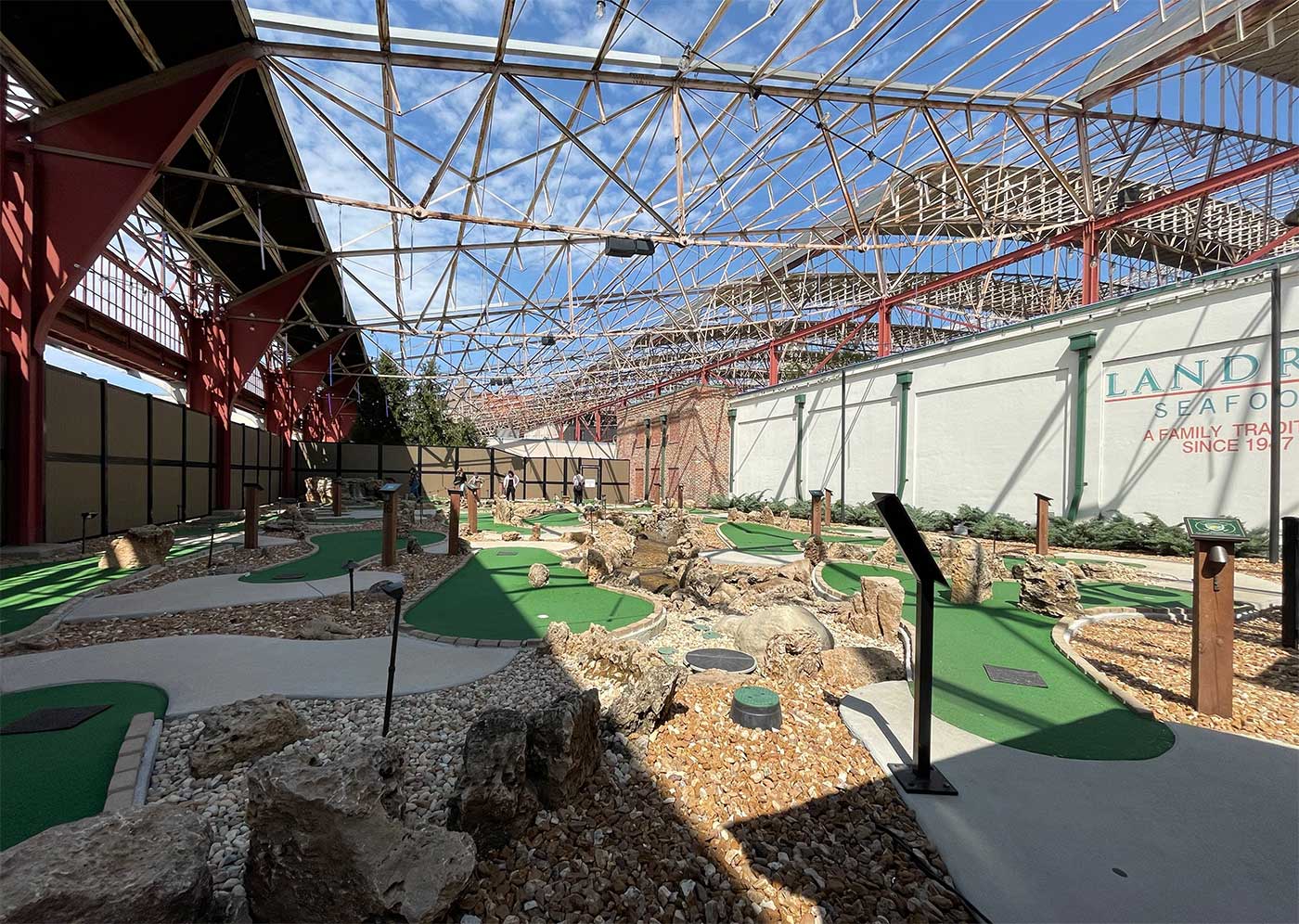 Flat mini golf course inside an old train station with an open rooftop.