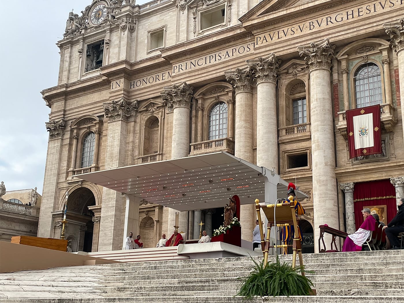 Steps of Saint Peter's Basilica, with Pope Francis seated in front of the coffin of Pope Benedict.