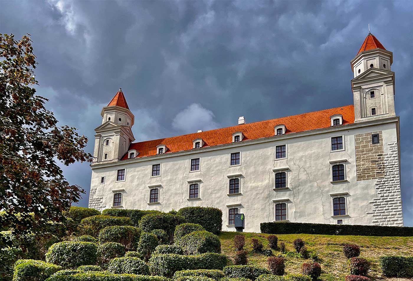 Exterior of castle with red turrets seen from a garden.