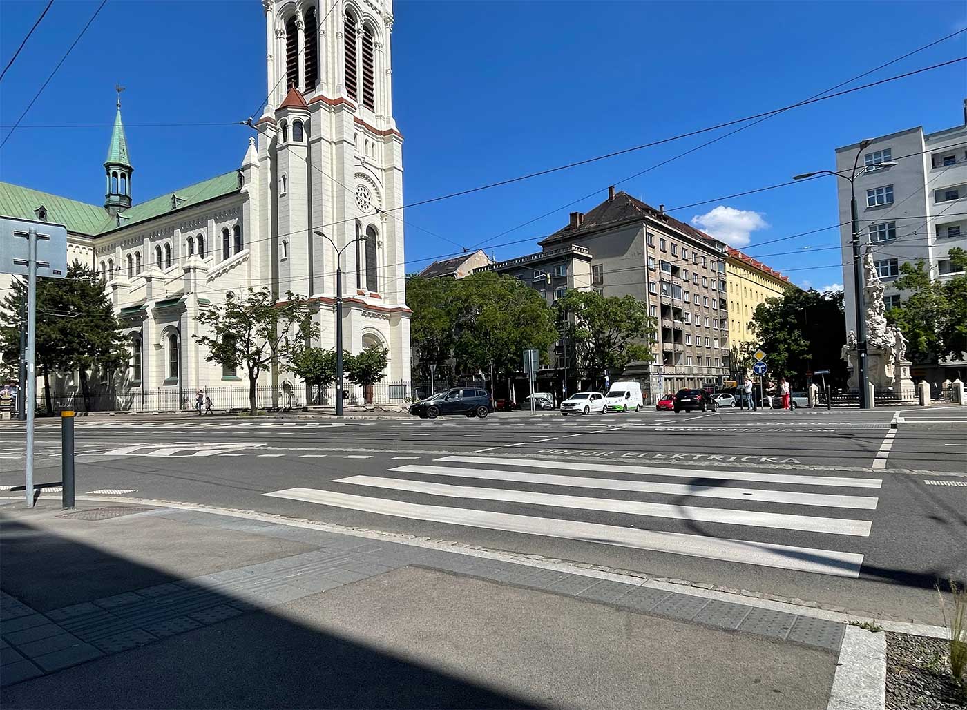 Intersection with accessible crosswalk and curb ramp, crossing signs and an easily accessible crossing button.